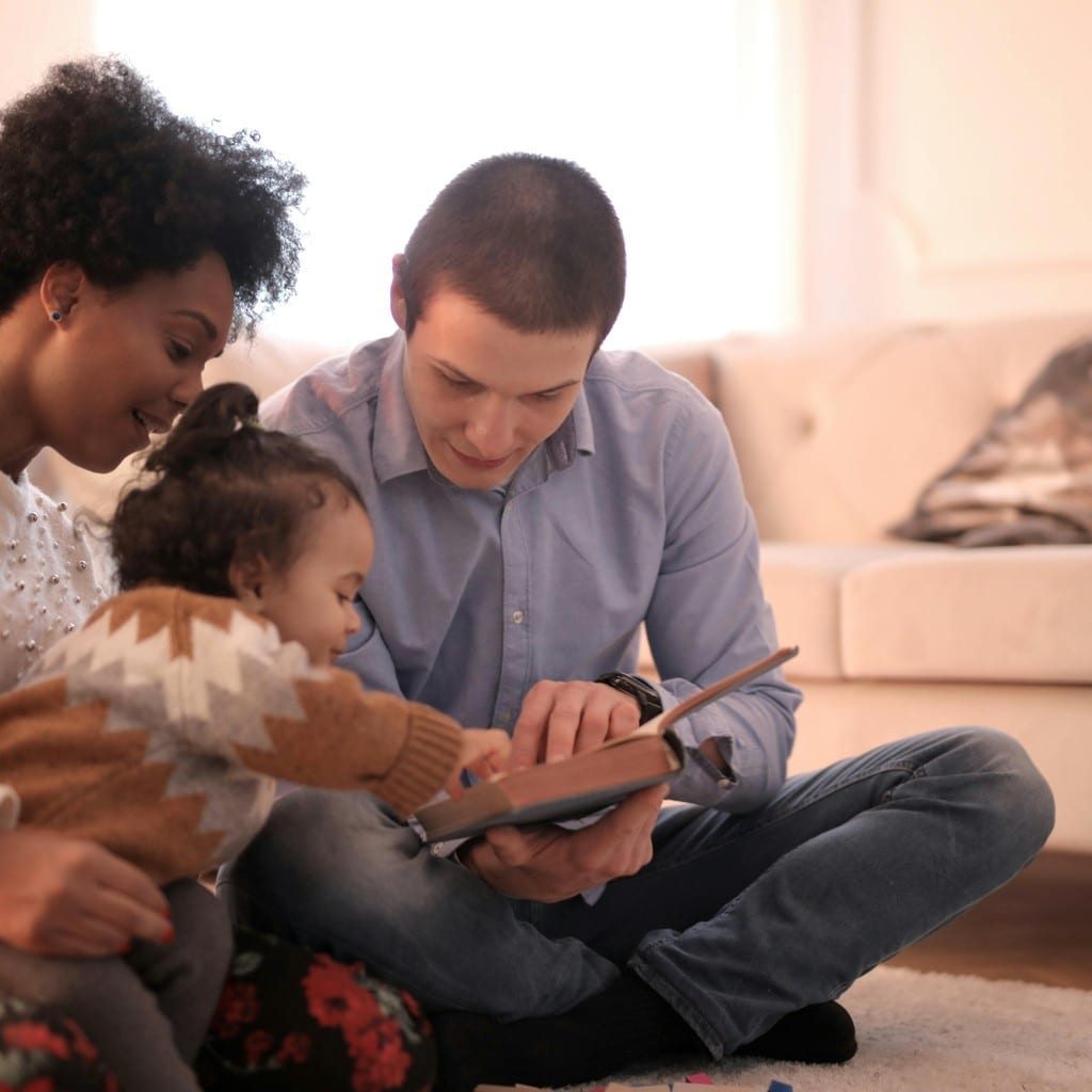 Familia disfrutando un libro juntos en el suelo de su casa